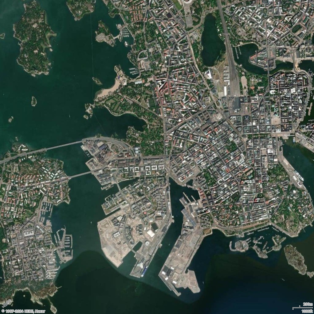 Aerial view of a coastal city with dense urban areas, harbors, and islands surrounded by water.