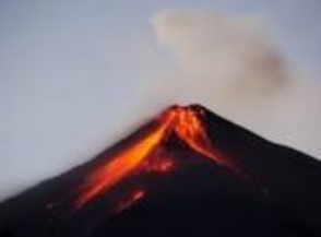 Gunung berapi meletus dengan lava cair mengalir di sisinya melawan langit berawan.